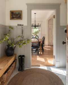 the wild decoelis | apple blossom branches in the house as decorations. Built in bench, refinished wood floors, black chairs, baskers, black vase, black chandelier, vintage art.